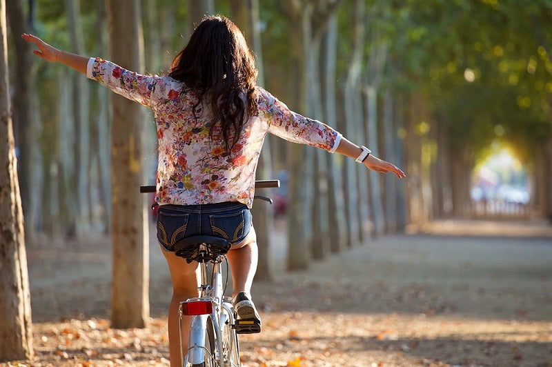 ragazza in bicicletta lungo un viale alberato