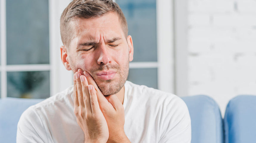 ragazzo che si tocca la guancia per il dolore