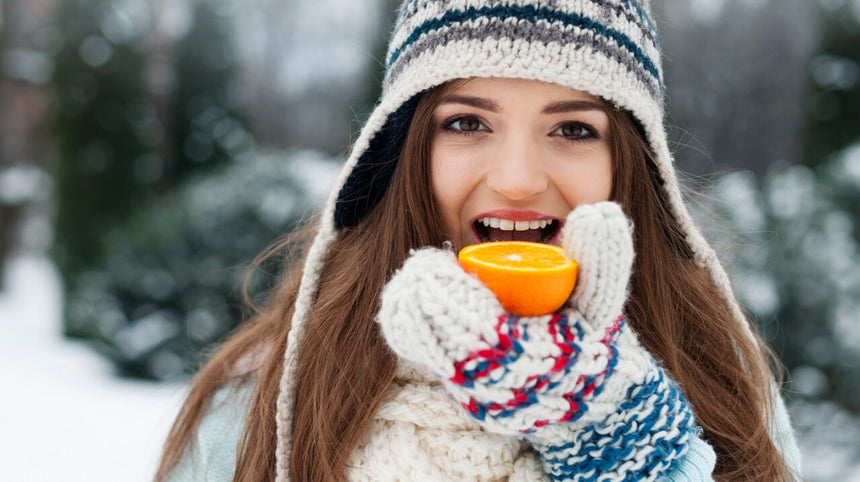 Ragazza in mezzo alla neve con arancia in mano