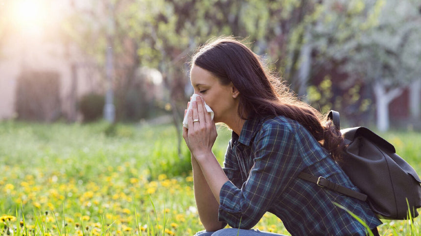 Ragazza che starnutisce seduta in un prato