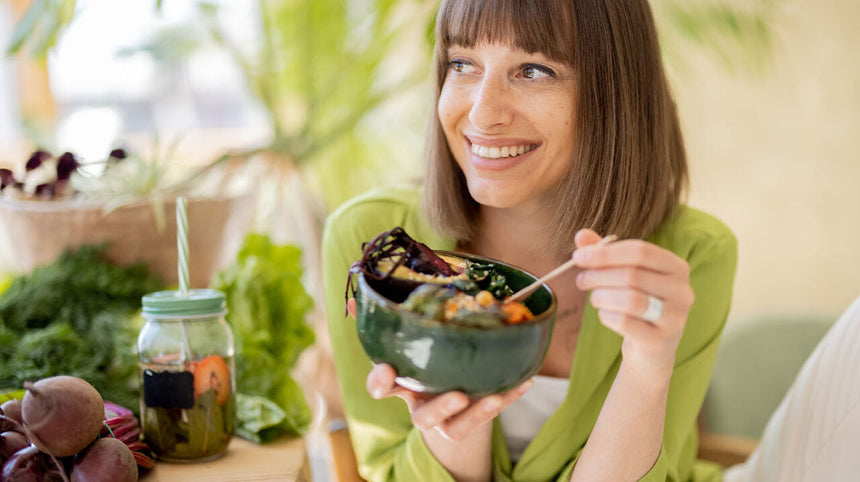 donna che mangia un'insalata sorridendo