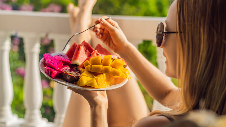 Ragazza che mangia piatto di frutta