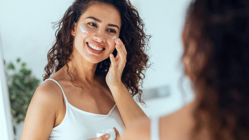 Ragazza allo specchio che si applica una crema viso