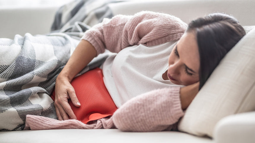 Donna a letto con la borsa dell'acqua calda sulla pancia