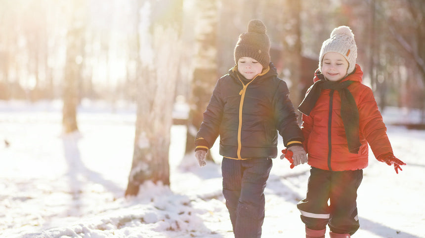 due bambini che camminano in un bosco innevato