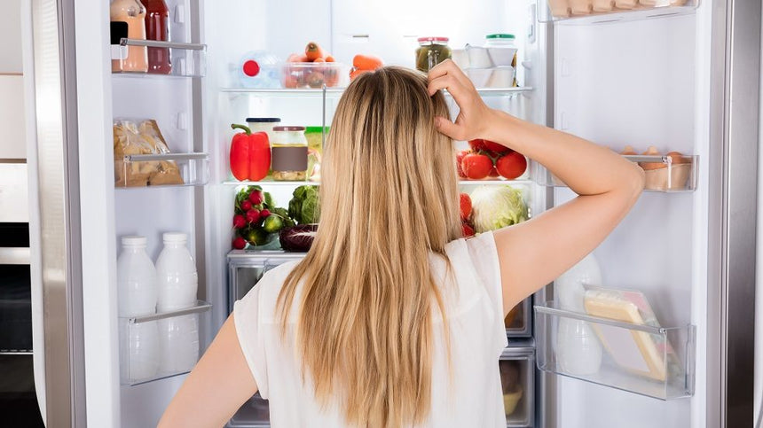 ragazza indecisa davanti al frigo aperto