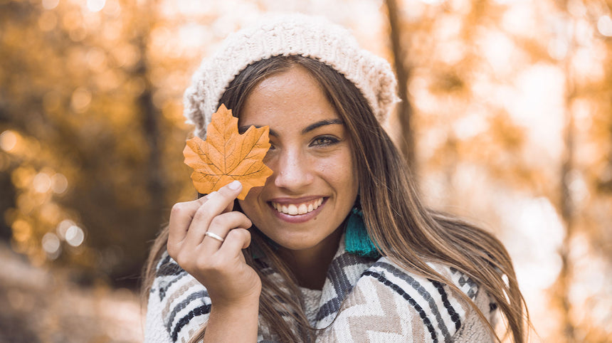 Ragazza che sorride tenendo una foglia davanti a un occhio