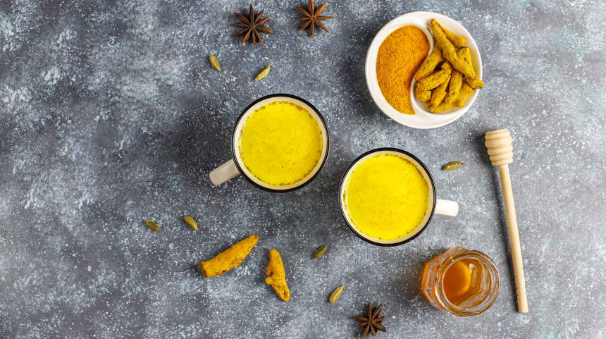 due tazze di latte d'oro con un piattino di curcuma