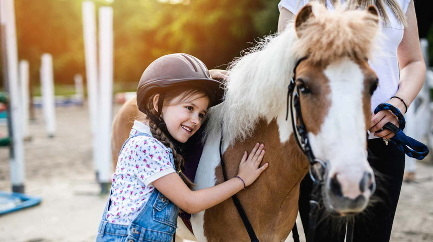 i benefici dell'ippoterapia: bambina che accarezza un pony