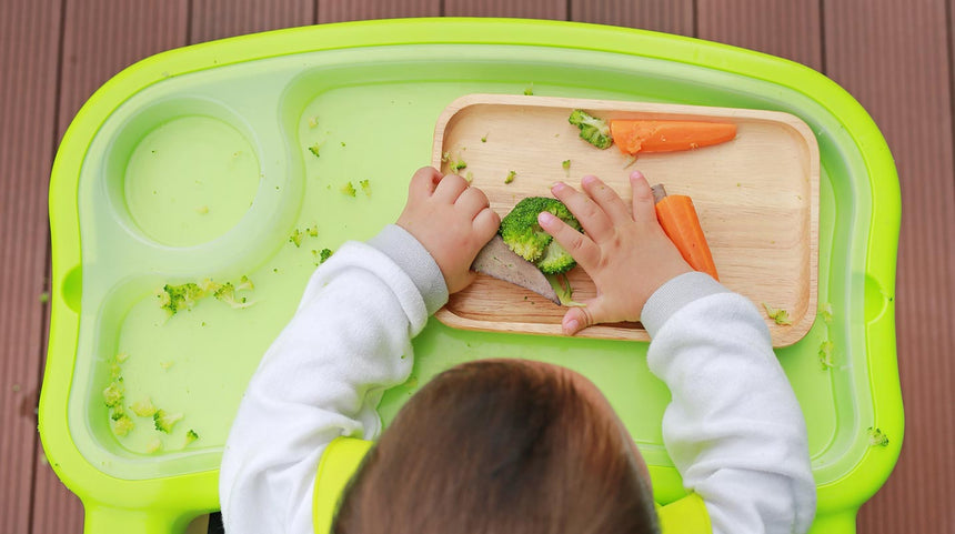 bambino mangia verdure su un seggiolone verde